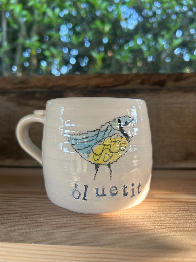 One of Sally's hand-painted mugs, on the shelf in her garden studio